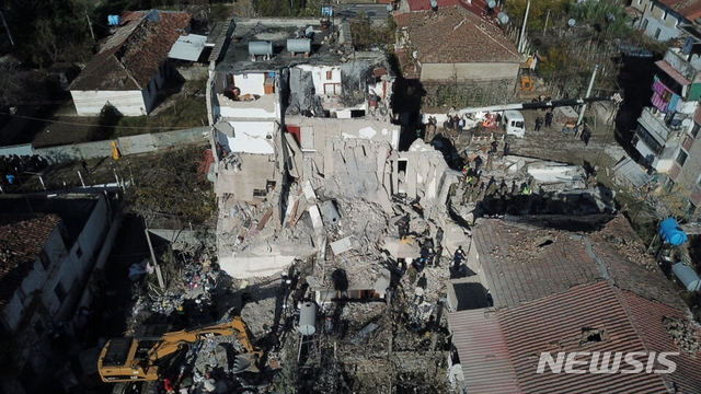 Rescuers search at a damaged building after a magnitude 6.4 earthquake in Thumane, western Albania, Tuesday, Nov. 26, 2019. Rescue crews used excavators to search for survivors trapped in toppled apartment buildings Tuesday after a powerful pre-dawn earthquake in Albania killed at least 14 people and injured more than 600. (AP Photo/Hektor Pustina)