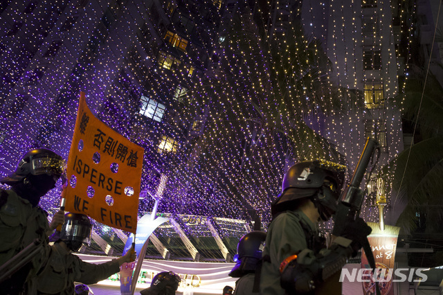 [홍콩=AP/뉴시스]1일(현지시간) 홍콩 시민들이 거리로 나와 시위를 벌인 가운데 홍콩 경찰이 이들을 향해 해산하라는 팻말을 들어 보이고 있다. 이날 시위에는 검은 옷과 마스크 차림의 청년뿐 아니라 아이들을 대동한 부모들도 상당수 함께했다. 2019.12.02.