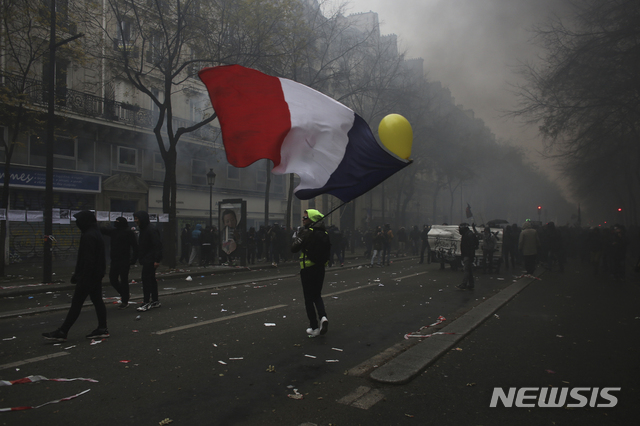 [파리=AP/뉴시스]5일(현지시간) 프랑스 수도 파리에서 열린 연금개혁 반대 시위에서 한 남성이 자욱한 연기 사이로 프랑스 국기를 흔들고 있다. 2019.12.6.