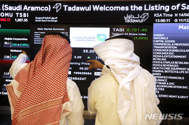[리야드-=AP/뉴시스] 11일 사우디 아람코 주식이 사우디 주식시장에 세계최초 상장되고 거래를 시작한 뒤 시장관계자들이 스크린을 주시하고 있다 2019. 12. 11.