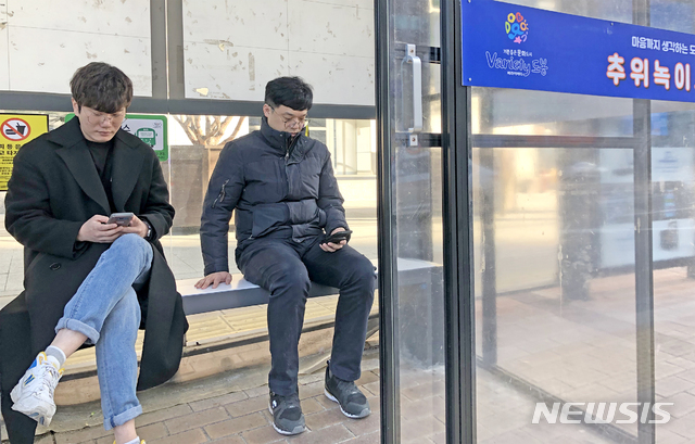 [서울=뉴시스]지난 17일 서울 도봉구의 한 버스정류소에 설치된 'IoT(사물인터넷) 온열의자'에 앉아 버스를 기다리는 시민들. 2019.12.30. (사진=도봉구 제공)