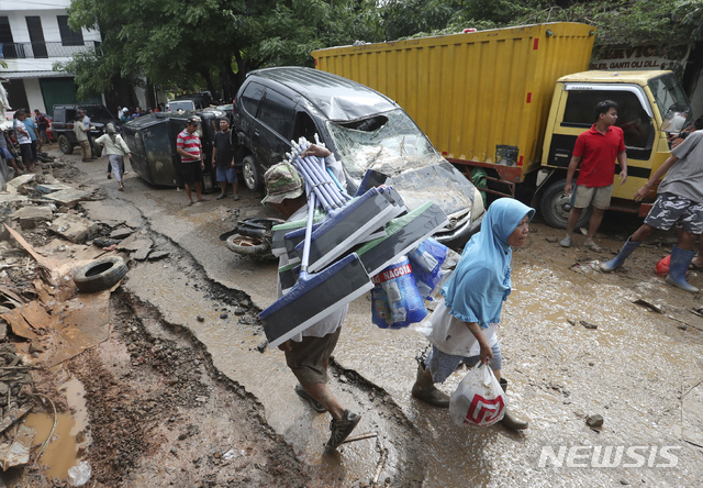[자카르타=AP/뉴시스]인도네시아 자카르타 수도권에 새해 첫날 발생한 홍수로 약 30명이 숨진 가운데 3일(현지시간) 자카르타 동쪽 브카시 마을 주민들이 홍수에 파손된 차량 주변을 지나고 있다. 2020.01.03.