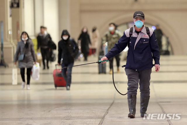 [우한=AP/뉴시스]신종 코로나바이러스가 발생한 중국 후베이성 우한시의 지하철역에서 22일 한 사람이 소독약을 뿌리고 있다. 뒤에 감염을 막으려고 마스크를 쓴 행인들이 보인다. 2020.01.23. 