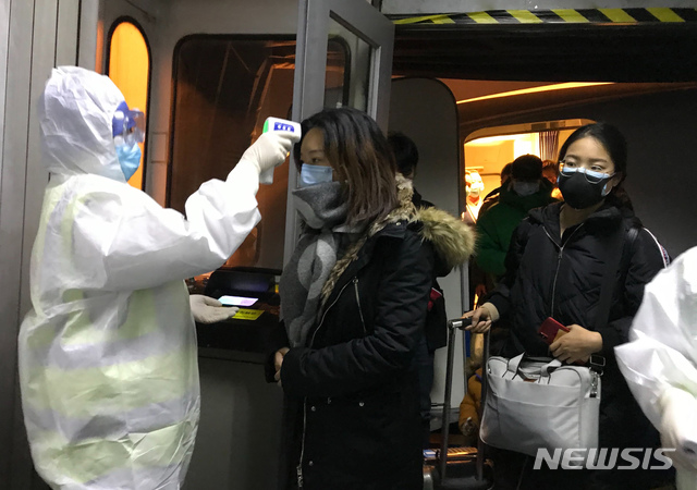 [베이징=AP/뉴시스]보호복을 입은 보건 관계자들이 22일 중국 베이징 공항에서 우한시에서 도착한 승객들의 체온을 체크하고 있다. 중국은 신종 코로나바이러스로 발생하는 폐렴의 확산을 막기 위해 23일부터 모든 항공기와 열차들의 우한 출발을 막기 시작했다. 2020.1.23