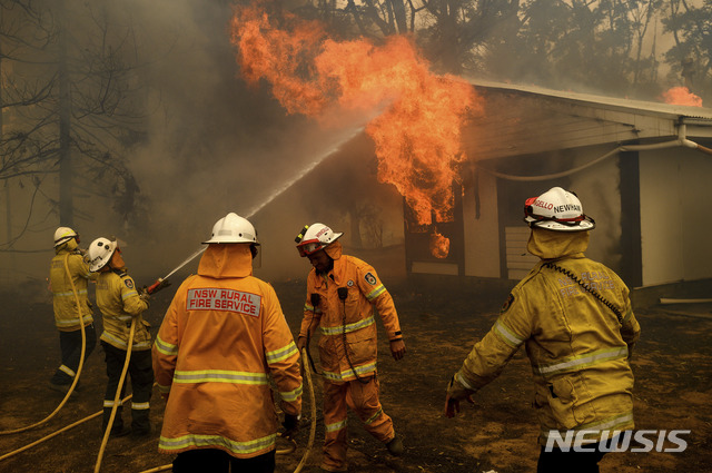 [번더눈=AP/뉴시스] 23일(현지시간) 호주 뉴사우스웨일스주 번더눈(Bundanoon) 인근 주택을 덮친 화재를 소방관들이 진압하려고 애쓰고 있다. 현재 호주 수도 캔버라 일대에서 발생한 산불이 확산하고 있다. 2020.01.23. 