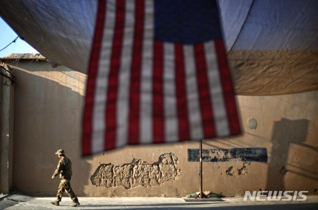 [ 카불( 아프가니스탄)= AP/뉴시스] 아프가니스탄에 주둔하고 있는 미군 제 27보병연대의 한 병사가 커다란 성조기가 드리워져 있는 막사 앞을 걸어가고 있다. (AP 자료사진) 미국은 18년간의 아프간 전쟁을 끝내고 미군을 철수시키기 위해 탈레반측과 평화협상을 진행중이다.