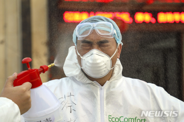 [우한=AP/뉴시스]중국 후베이성 우한의 한 격리시설에서 3일 보호복을 입은 한 의료 요원이 소독약이 뿌려지는 동안 눈을 감고 있다. 우한의 의료진은 신종 코로나 사태로 격무와 감염 위험에 시달리고 있다. 2020.02.12 