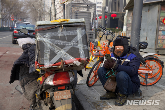 [베이징=AP/뉴시스]11일 중국 베이징거리에서 한 배달원이 휴대전화를 들여다 보고 있다. 시진핑 중국 국가주석이 신종 코로나바이러스 감염증(우한 폐렴) 방역 업무가 진행되는 현장을 찾은 가운데 중국의 하루 사망자와 누적 사망자 수가 처음으로 각각 100명과 1000명을 넘어섰다고 현지 관계자가 밝혔다. 2020.02.11. 