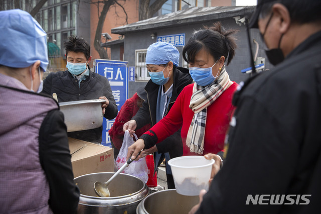 [베이징=AP/뉴시스]21일 중국 베이징의 한 상가 건물 앞에서 마스크를 쓴 여성들이 음식을 팔고 있다. 중국 국가위생건강위원회 이날 0시 기준 코로나19 확진자가 889명 증가했다고 발표했다. 2020.02.21.