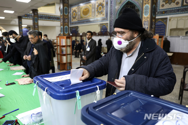 [테헤란=AP/뉴시스]21일(현지시간) 이란 수도 테헤란의 한 투표소에서 마스크를 쓴 한 남성이 투표하고 있다. 이날 이란 의회 의원을 뽑는 선거가 열려 4년 임기의 의원 290명을 뽑는다. 이란은 만 18세 이상 남녀는 모두 참정권을 행사할 수 있으며 이번 총선에서 5천800만 명이 유권자로 등록됐다. 2020.02.21.