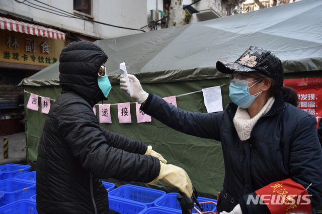 [우한=AP/뉴시스]지난 21일 마스크를 작용한 한 시민이 중국 후베이성 우한의 한 주택가로 들어가기 전 체온을 체크하고 있다. 2020.02.22.
