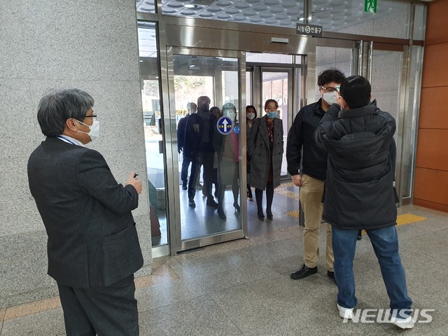 용인시 공무원들이 27일 용인시청 후문 출입구에서 발열체크를 받고 손을 소독하며 출근하고 있다.