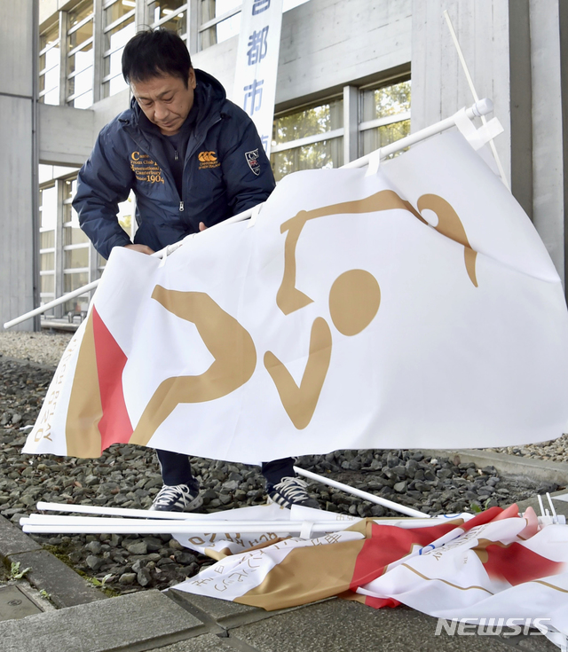 [이나자와=AP/뉴시스]25일 일본 아이치현 이나자와 시청에서 한 작업자가 도쿄 올림픽·패럴림픽이 2021년으로 연기되면서 성화봉송도 연기돼 관련 현수막을 철거하고 있다. 2020.03.25.