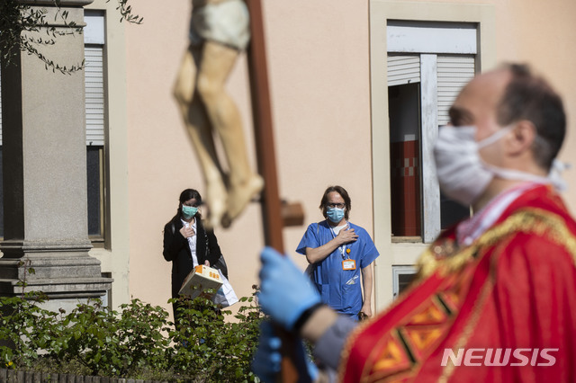[바레세=AP/뉴시스]부활절을 앞둔 성금요일인 10일(현지시간) 이탈리아 바레세의 한 병원에서 한 신부가 마스크를 쓴 채 '십자가의 길' 행사를 이끌고 있다. 2020.4.11.