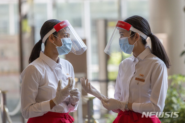 [방콕=AP/뉴시스]지난 14일 태국 방콕의 한 쇼핑몰에서 신종 코로나바이러스 감염증(코로나19) 예방을 위해 마스크와 페이스 실드를 착용한 직원들이 장갑을 착용하고 있다. 2020.05.16.