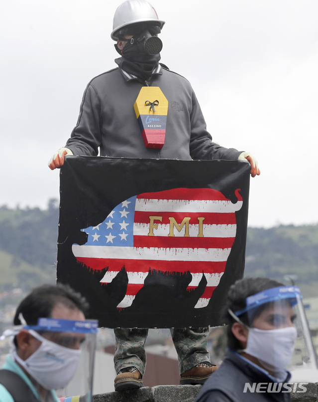 [키토=AP/뉴시스]18일(현지시간) 에콰도르 키토에서 다수의 노동조합이 주최한 시위가 열려 마스크를 쓴 한 참가자가 IMF 깃발을 들고 시위에 동참하고 있다. 시위대는 15일 밤 통과한 노동관련법안이 "고용주에게 혜택을 주고 노동자들을 위험에 빠뜨린다"고 주장하며 이에 반대하는 시위를 펼쳤다. 2020.05.19.