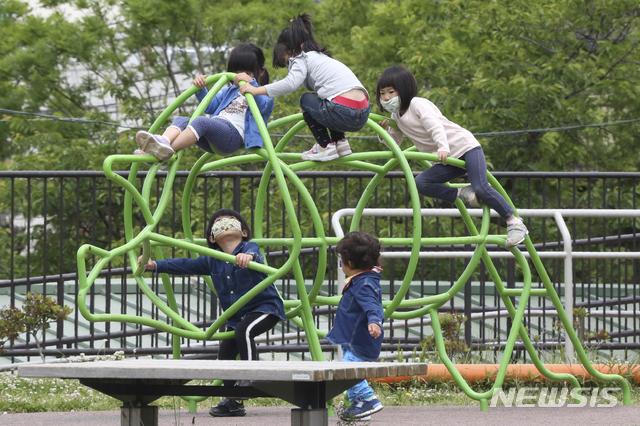 [요코하마=AP/뉴시스]지난달 20일 일본 도쿄 인근 가나가와현 요코하마의 한 공원에서 신종 코로나바이러스 감염증(코로나19) 예방을 위해 마스크를 쓴 어린이들이 놀이기구를 타며 놀고 있다. 2020.05.20. 