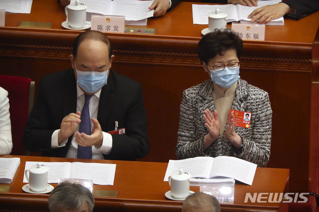 [베이징=AP/뉴시스]22일(현지시간) 중국 베이징 인민대회당에서 중국 최대 정치 행사인 전국인민대표회의(전인대)가 열렸다. 캐리 람 홍콩 행정장관(오른쪽)이 신종 코로나바이러스 감염증(코로나19)을 막기 위해 마스크를 쓴 채 참석해 박수 중인 모습. 2020.05.22.  