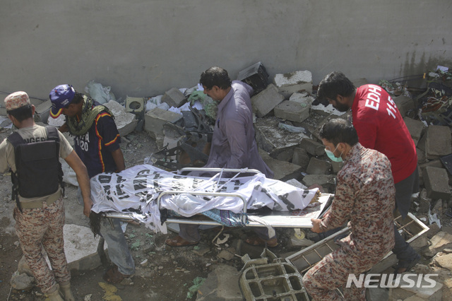Volunteers carry the dead body of plane crash victim in Karachi, Pakistan, Friday, May 22, 2020. An aviation official says a passenger plane belonging to state-run Pakistan International Airlines carrying more than 100 passengers and crew has crashed near the southern port city of Karachi. (AP Photo/Fareed Khan)