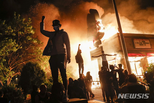  [미니애폴리스=AP/뉴시스] 29일(현지시간) 미국 미네소타주 미니애폴리스에서 시위대가 불타는 패스트푸드 매장 앞에서 손을 번쩍 들고 있다. 비무장 상태로 경찰에게 목이 짓눌려 사망한 흑인 조지 플로이드 사건에 항의하는 시위는 연일 격화하고 있다. 2020.05.30. 