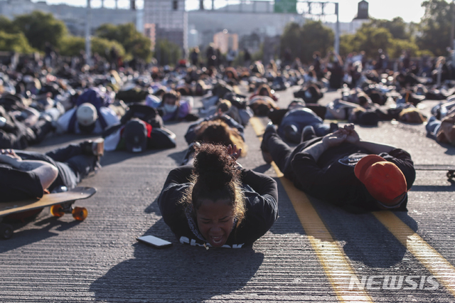 [포틀랜드=AP/뉴시스]미국 오리건주 포틀랜드에서 1일9현지시간) 조지 플로이드 사망 항의 시위 참석자들이 손을 뒤로 하고 땅에 엎드려 플로이드 사망 당시 모습을 재연하고 있다. 2020.06.03. 