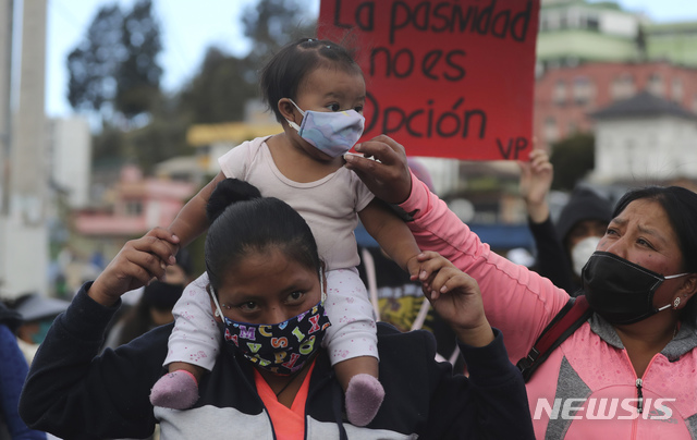 [키토=AP/뉴시스]16일(현지시간) 에콰도르 키토에서 한 여성이 반정부 시위 도중 한 아기의 마스크를 매만져주고 있다. 수도에서 코로나19가 날로 증가해 모임을 하지 말라는 당국의 권고에도 불구하고 시위가 이어지고 있다. 2020.07.17.