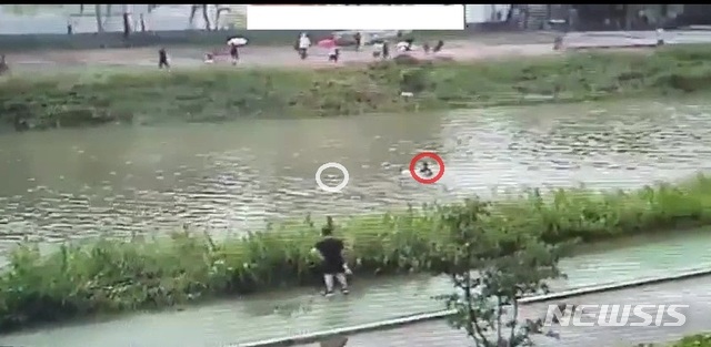 인근 CCTV에 잡힌 당시 구조 모습. 중랑천에 뛰어든 경찰관(빨간원)이 떠내려가는 아이(흰색원)를 쫓아가고 있다. (사진=경기북부지방경찰청 제공)