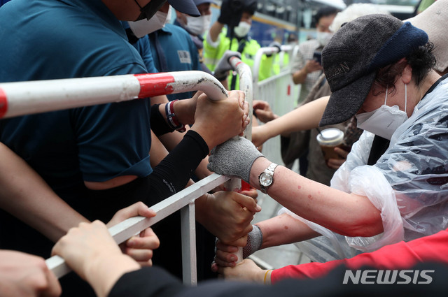 [서울=뉴시스]추상철 기자 =보수단체 집회 참가자가 15일 오전 서울 종로구 광화문광장에서 8·15 국민대회 집회중 경찰이 세워놓은 바리게이트를 넘으려고 시도하고 있다. 2020.08.15. scchoo@newsis.com