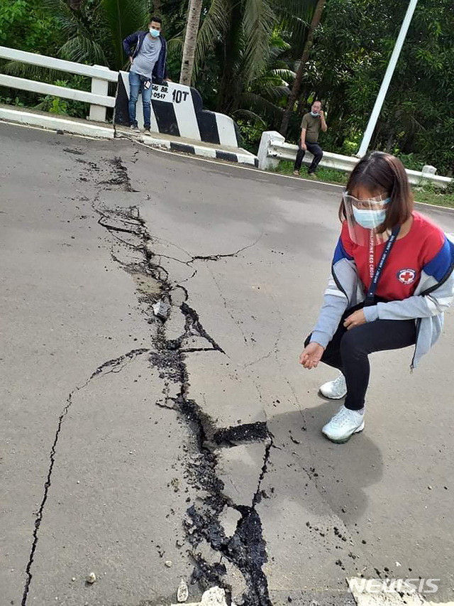 [카타인간(필리핀)=AP/뉴시스]필리핀 적십자사가 제공한 사진에 18일(현지시간) 필리핀 중부 마스바테주 카타인간에서 규모 6.5의 지진이 발생해 한 자원봉사자가 갈라진 도로를 가리키고 있다. 현지 관계자는 이 지진으로 주민들이 건물 밖으로 뛰쳐나오는 등 대피했으며 아직 피해 사례는 보고되지 않았다고 밝혔다. 2020.08.18.