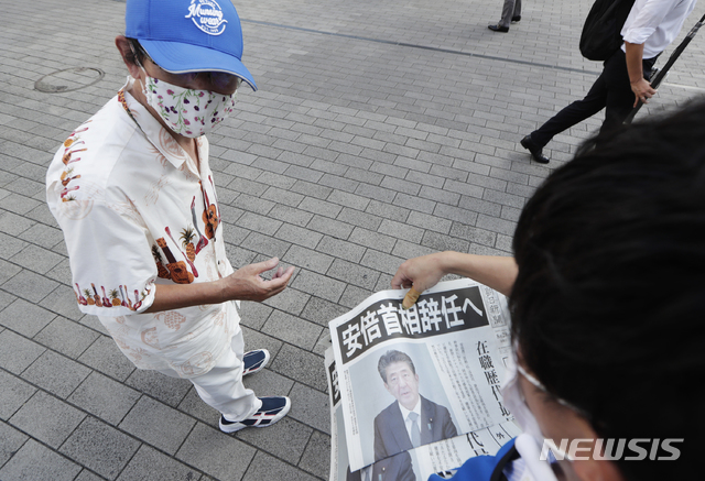 [도쿄=AP/뉴시스] 지난 8월 28일 일본 도쿄에서 아사히 신문의 호외가 시민들에게 전달되고 있다. 아베 신조 전 총리가 사임 의사를 발표한 내용의 호외다. 2020.12.01.