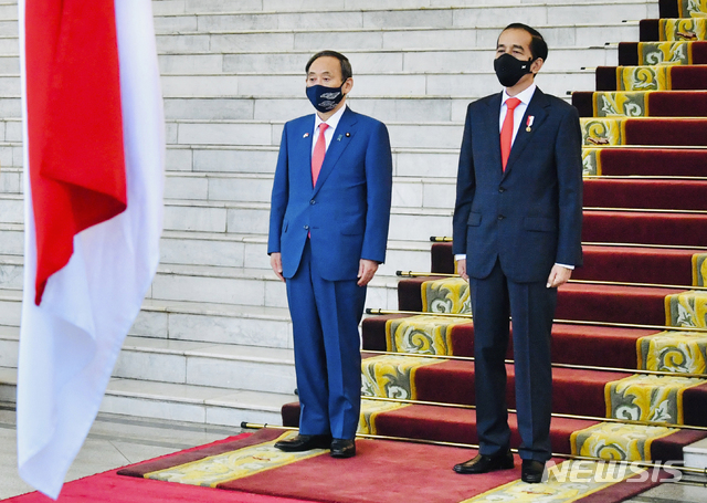 [자카르타=AP/뉴시스] 스가 요시히데 일본 총리(왼쪽)가 20일 인도네시아 수도 자카르타 외곽에 있는 보고르 대통령궁에서 열린 환영식에서 조코 위도도 인도네시아 대통령과 함께 양국 국가 연주를 듣고 있다. 2020.10.21. 