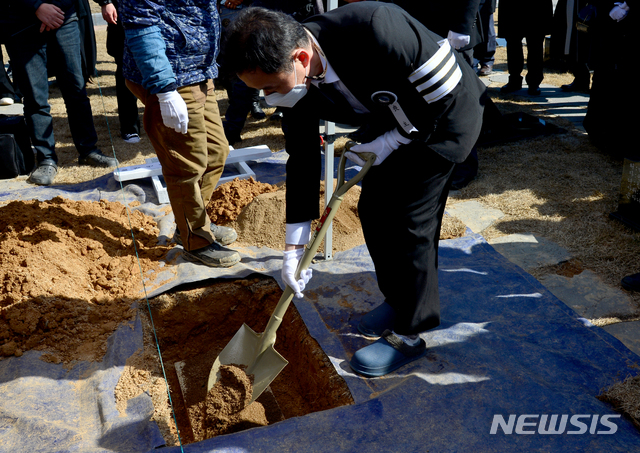 [광주=뉴시스] 김혜인 기자 = 고(故) 강신석 목사의 유가족이 8일 오후 광주 북구 운정동 국립 5·18민주묘지 2묘역에서 봉분에 앞서 흙을 유골함 위에 뿌리고 있다. 2021.02.08.hyein0342@newsis.com