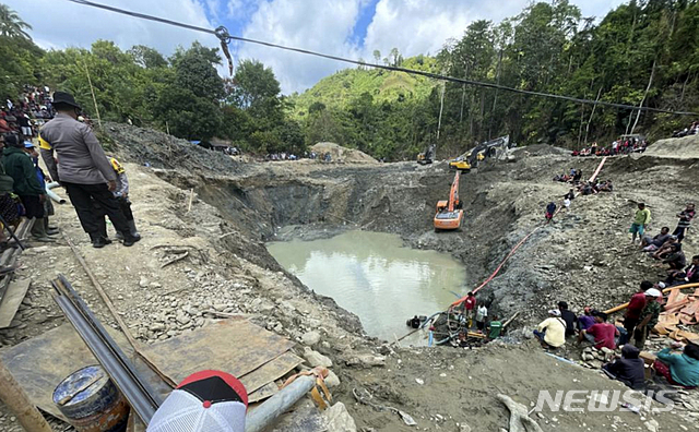 [파리기 무통=AP/뉴시스] 25일 인니 슬라웨시 섬에서 전날 밤 무너진 불법 금 채굴장에서 구조대가 물을 빼내고 있다