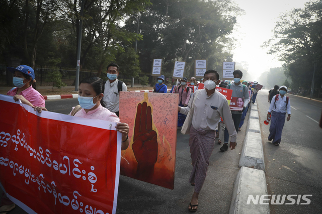 [양곤=AP/뉴시스]26일 미얀마 양곤에서 대학교수들이 군부 쿠데타 반대 시위에 참가자들의 서명이 담긴 대형 세 손가락 그림을 들고 행진하고 있다. 2021.02.26.