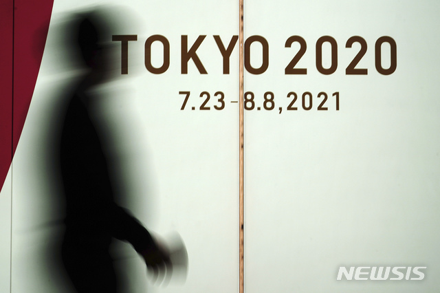 [도쿄=AP/뉴시스]17일 일본 도쿄에서 코로나19 확산을 막기 위해 마스크를 쓴 한 남성이 2020 도쿄 올림픽 광고판 앞을 지나고 있다. 도쿄도는 이날 하루 코로나19 신규 확진자가 400명 이상 발생했다고 발표했다. 2021.03.17.