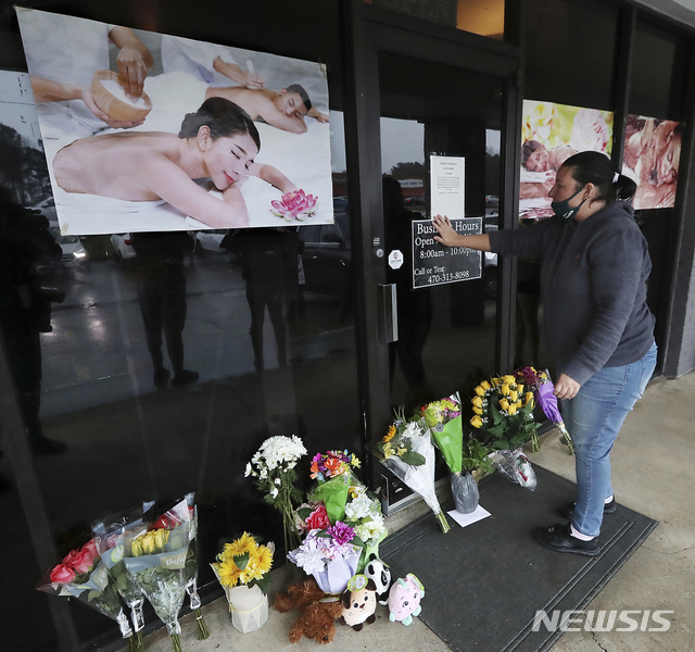[액워스=AP/뉴시스]지난 3월17일(현지시간) 미 조지아주 '애틀랜타 총격'으로 4명이 숨진 애크워스의 영 아시안 마사지 숍 앞에서 한 여성이 꽃다발을 들고 희생자들을 애도하고 있다. 2021.05.12.