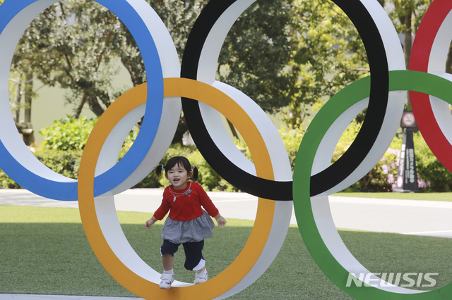 [도쿄=AP/뉴시스]20일 일본 도쿄에서 한 어린이가 올림픽을 상징하는 오륜 조형물에서 놀고 있다. 2021.04.20.
