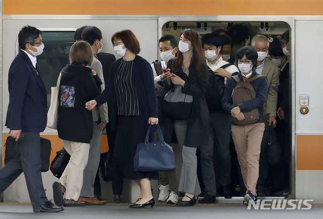 [도쿄=AP/뉴시스]지난 6일 일본 도쿄의 한 역에 정차한 열차에서 마스크를 착용한 통근자들이 내리고 있다. 2021.05.07.