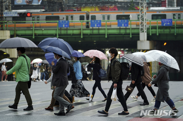 [도쿄=AP/뉴시스]13일 일본 도쿄에서 코로나19 확산을 막기 위해 마스크를 쓴 시민들이 우산을 쓰고 건널목을 건너고 있다. 도쿄도는 이날 1010명의 코로나19 신규 환자를 확인했다고 밝혔다. 2021.05.13.