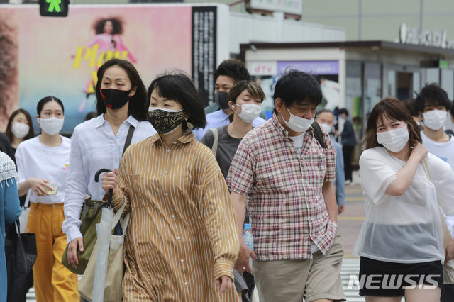 [도쿄=AP/뉴시스]18일 일본 도쿄에서 코로나19 감염을 예방하기 위해 마스크를 착용한 시민들이 거리를 걷고 있다. 2021.05.18.