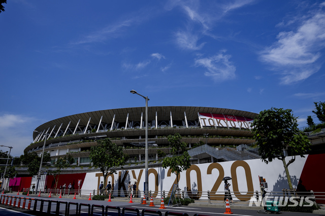 [도쿄=AP/뉴시스]지난 10일 일본 도쿄 국립경기장 앞을 마스크를 착용한 시민들이 걸어가고 있다. 도쿄올림픽 경기가 열리는 이 경기장 앞에는 '도쿄 2020' 슬로건이 보인다. 2021.07.135