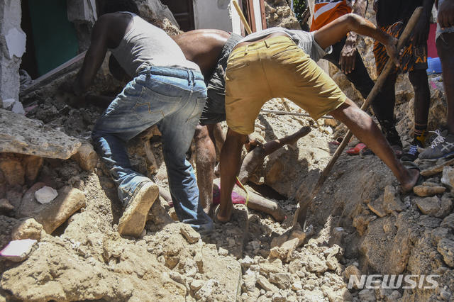 [포르토프랭스( 아이티)= AP/뉴시스] 건물 잔해에 묻힌 사람들의 시신을 파내고 있는 마을 사람들. 