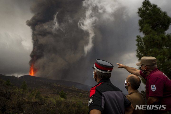[라팔마=AP/뉴시스] 스페인 카나리아제도 라 팔마 섬에 있는 쿰브레 비에호 화산 폭발 현장 인근에서 22일(현지시간) 현지 경찰과 작업자들이 분출하는 용암을 살펴보고 있다. 약 50년 만의 화산 폭발로 320여 채의 가옥이 파손되고 수천 명의 주민이 대피한 가운데 산업통상관광부 장관은 이 화산폭발을 '멋진 쇼'라고 말해 논란이 됐다. 전문가들은 이번 폭발 여파가 80일 이상 지속할 것이라고 관측했다. 2021.09.23.