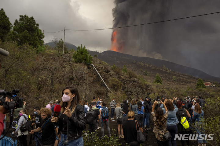 [라팔마=AP/뉴시스] 스페인 카나리아제도 라 팔마 섬에 있는 쿰브레 비에호 화산 폭발 현장 인근에서 22일(현지시간) 기자들이 취재하고 있다. 약 50년 만의 화산 폭발로 320여 채의 가옥이 파손되고 수천 명의 주민이 대피한 가운데 산업통상관광부 장관은 이 화산폭발을 '멋진 쇼'라고 말해 논란이 됐다. 전문가들은 이번 폭발 여파가 80일 이상 지속할 것이라고 관측했다. 2021.09.23.