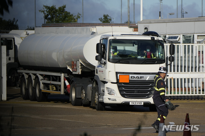 [헤멜헴프스테드=AP/뉴시스] 5일(현지시간) 영국 헤멜 헴프스테드 인근 번스필드 유류고에서 한 근로자가 연료 트럭 안의 동료에게 손을 흔들고 있다. 영국 군인들이 대형 트럭 운송 기사 부족으로 1주일 넘게 기름이 부족한 영국 내 주유소에 연료 수송을 시작했다. 당국은 약 200명의 운전병이 연료 수송 작전에 합류했다고 밝혔다. 2021.10.05.