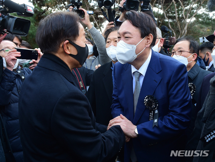 [서울=뉴시스] 국회사진기자단 = 윤석열 국민의힘 대선 후보가 22일 서울 동작구 국립서울현충원 내 김영삼 전 대통령 묘역에서 열린 6주기 추모식에서 차남인 김현철 김영삼민주센터 상임이사와 인사를 나누고 있다. 2021.11.22. photo@newsis.com