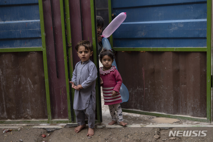 [헤라트=AP/뉴시스] 23일(현지시간) 아프가니스탄 헤라트의 한 가정집 문 앞에서 어린이들이 호기심 어린 표정으로 카메라를 바라보고 있다. 2021.11.24.