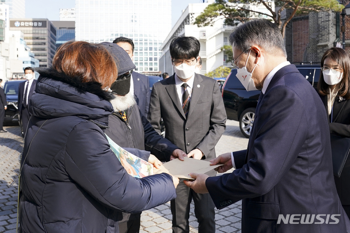 [서울=뉴시스] 전진환 기자 = 문재인 대통령이 25일 국가인권위원회 설립 20주년 기념식이 열린 서울 중구 명동성당 꼬스트홀 앞에서 고 이예람 중사 부모로부터 면담요청 등 요구사항이 담긴 입장문을 받고 있다. 2021.11.25. amin2@newsis.com