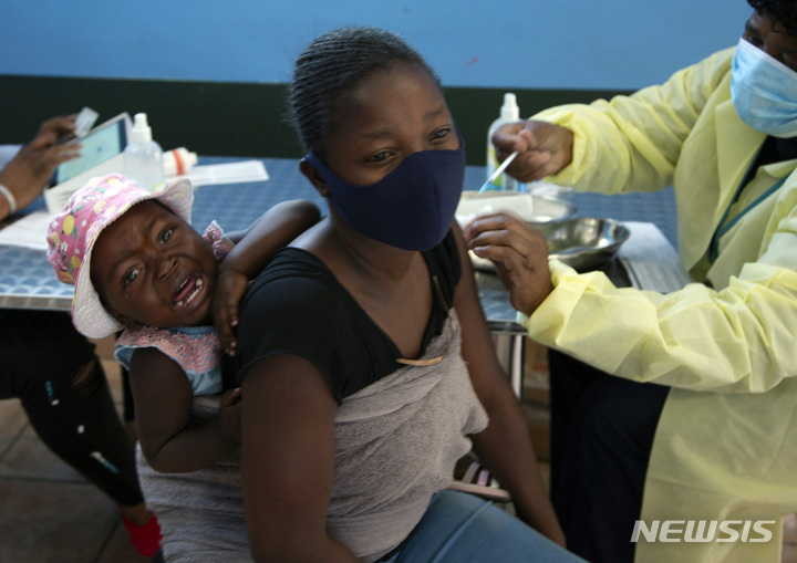 [요하네스버그=AP/뉴시스] 10월 21일 남아공 요하네스버그 인근에서 아기를 업은 한 여성이 백신을 접종하는 모습. 2021.11.26.