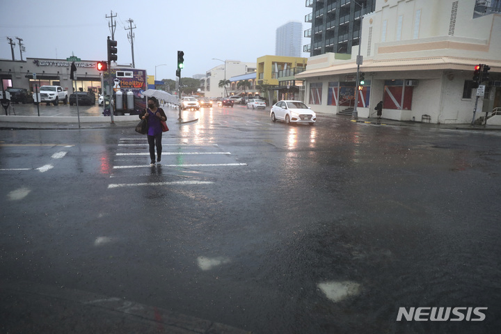 [호놀룰루=AP/뉴시스] 6일(현지시간) 미 하와이주 호놀룰루에서 시민이 우산을 쓴 채 길을 건너고 있다. 2021.12.07.